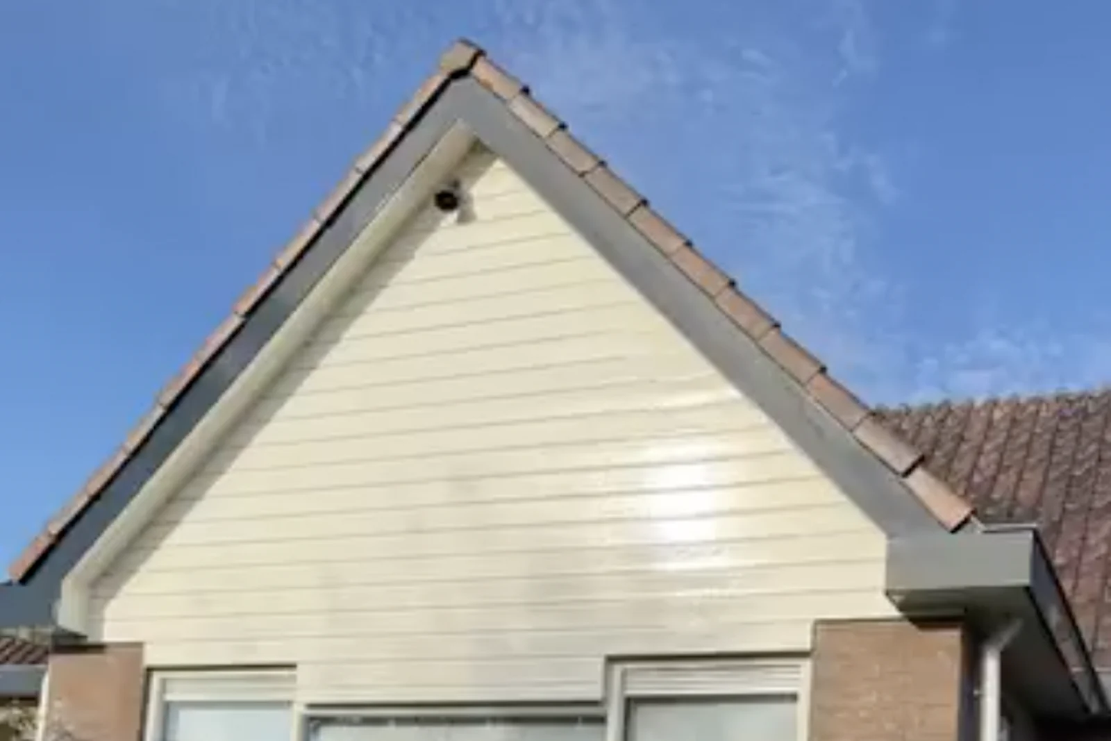 Geveltop vóór het schilderwerk: de houten betimmering is vergeeld en dof