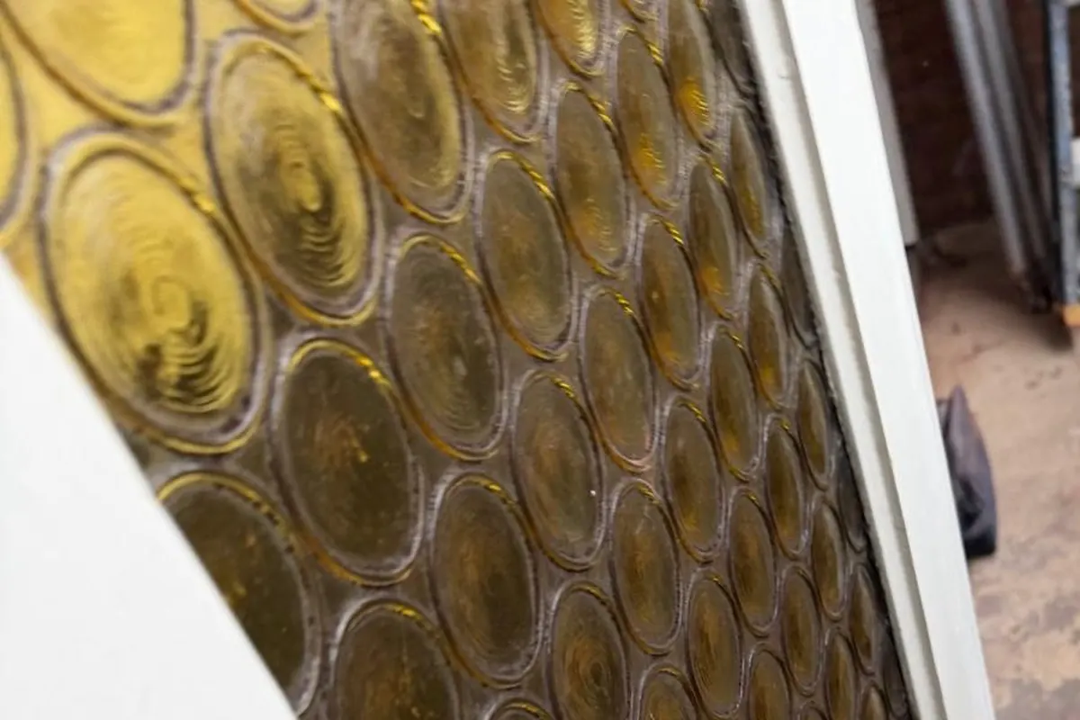 Detail van glas-in-lood met ronde, goudkleurige ruiten in een witte deur