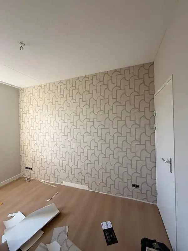 Kamer met een behangen accentwand en houten vloer