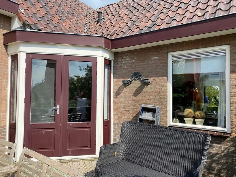 Bordeauxrode openslaande deuren in een erker met wit kozijnwerk