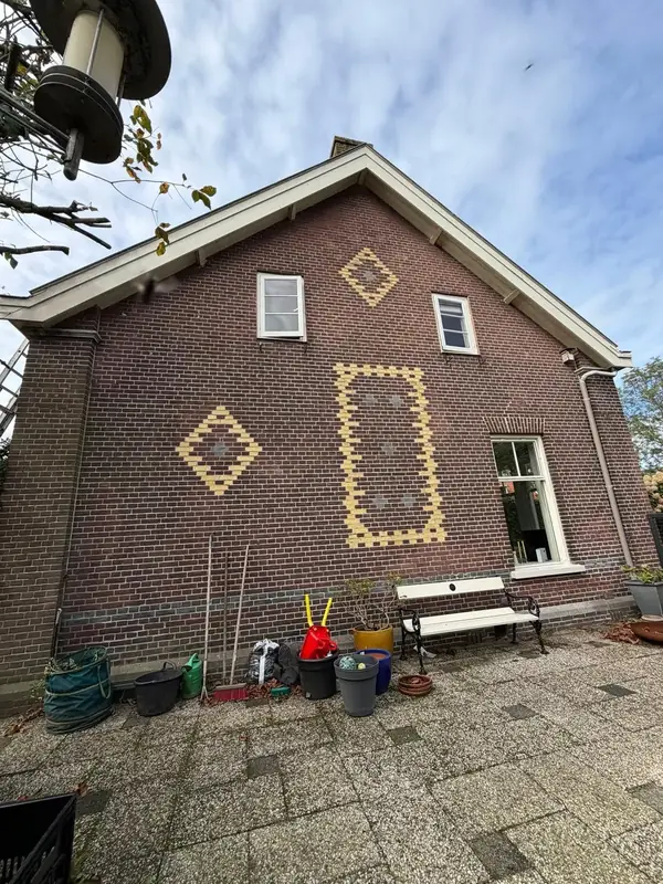 Bakstenen zijgevel met decoratief metselwerk en vers kozijnwerk