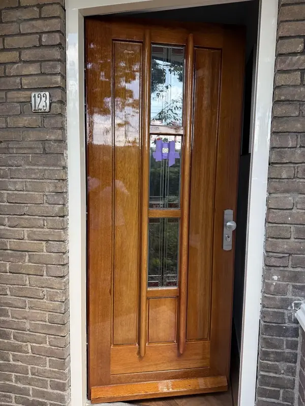 Houten voordeur met glanzende, warme afwerking in een wit kozijn