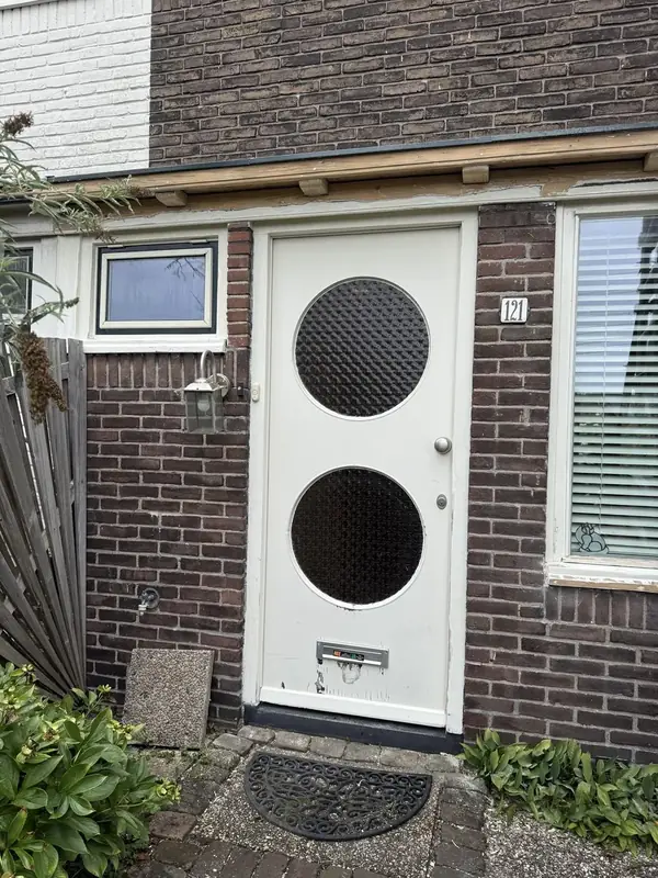 Witte voordeur met twee ronde ramen in een bakstenen gevel